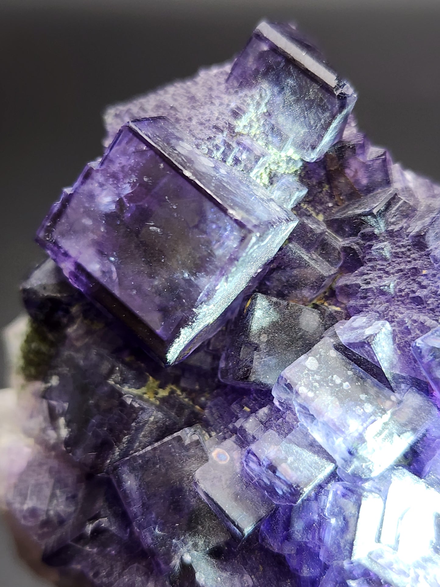 Close-up of a vibrant Fluorite mineral from Larkin's Quarry, Shannapheasteen, showcasing high luster cubes in a medium cluster. The transparent and reflective crystals are highlighted under bright light, revealing various shades of purple and subtle hints of green. This intricate structure by The Crystalary is reminiscent of the distinctive finds from Costelloe, Connemara in Galway County, Connacht, Ireland.