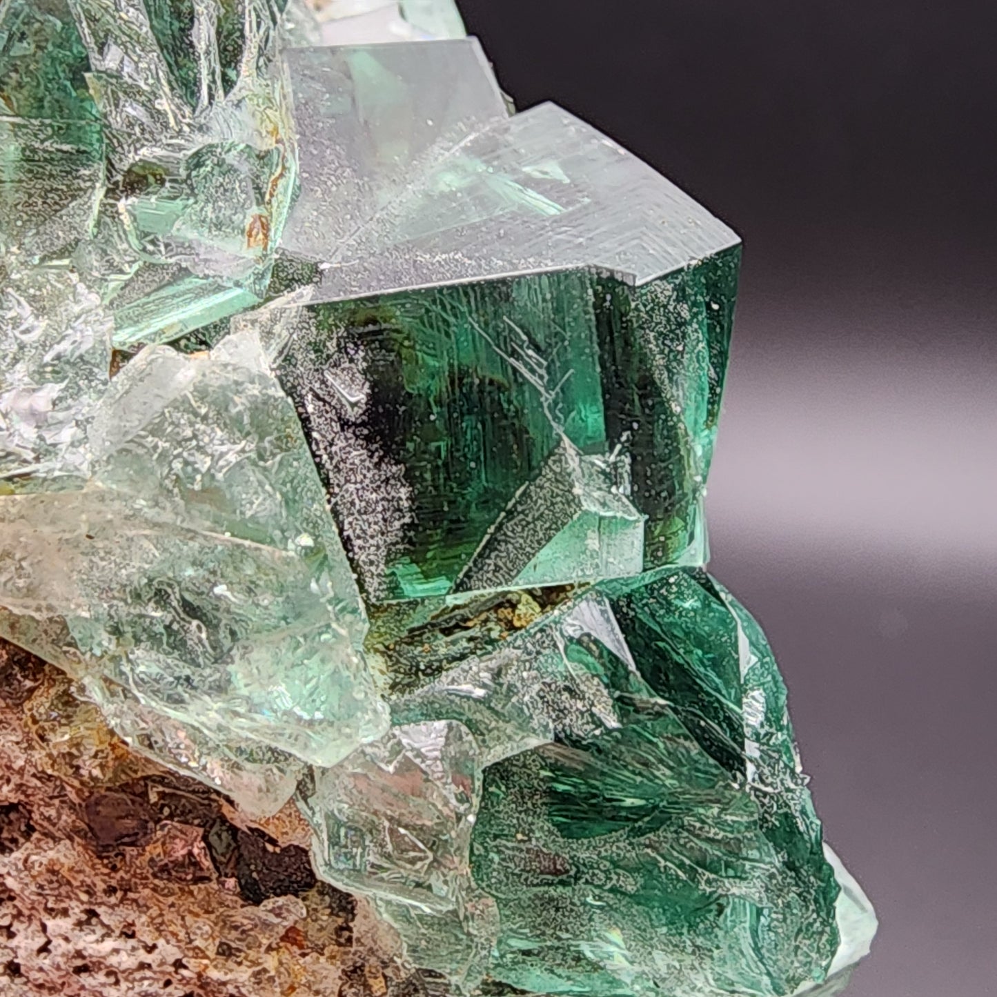 A close-up of a cluster of translucent green fluorite crystals from The Crystalary's "Greedy Hog Pocket" collection, sourced from the Diana Maria Mine in Co Durham, UK, SKU 3071. Against a dark background, these crystals showcase vivid color and intricate texture, evoking treasures from Greedy Hog Pocket.