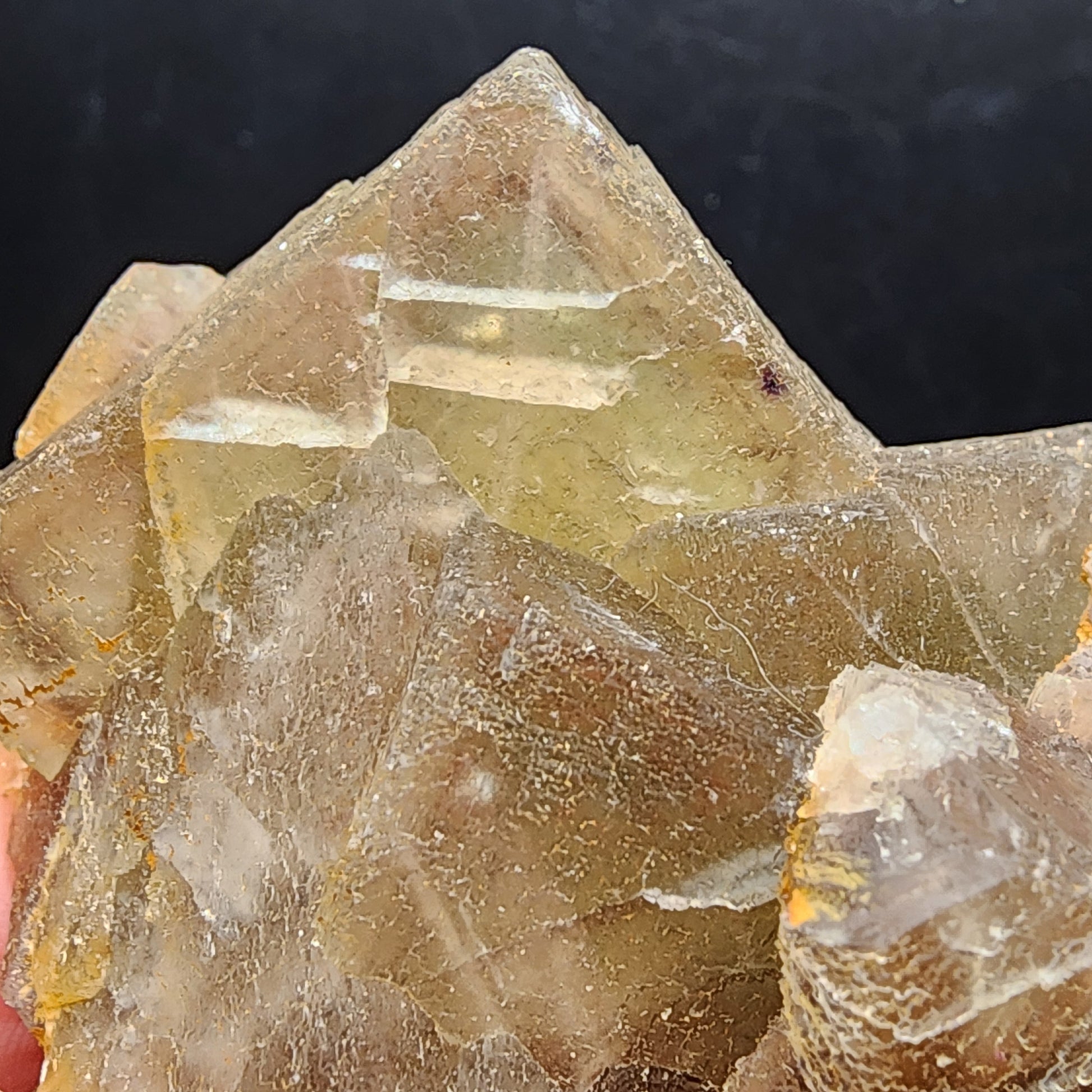 In the foreground, a close-up of a cluster of translucent, brownish-gold calcite crystals with sharp, angular shapes is set against a dark background. These striking crystals evoke the enigmatic allure seen in treasures like The Crystalary's Fluorite from the Heißer Stein Mine in Stulln (SKU 3080).