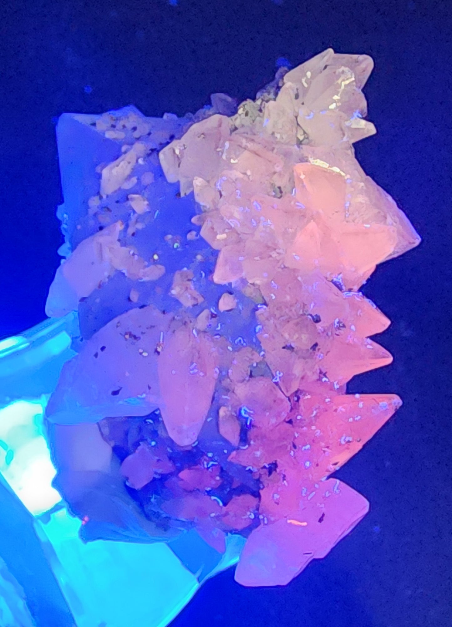 The Crystalary's Quartz v. Amethyst, Calcite (SKU 3100) from Tonglushan Mine features translucent, jagged amethysts that capture a vibrant blue-pink gradient against a dark backdrop, creating an ethereal and colorful gemstone effect.