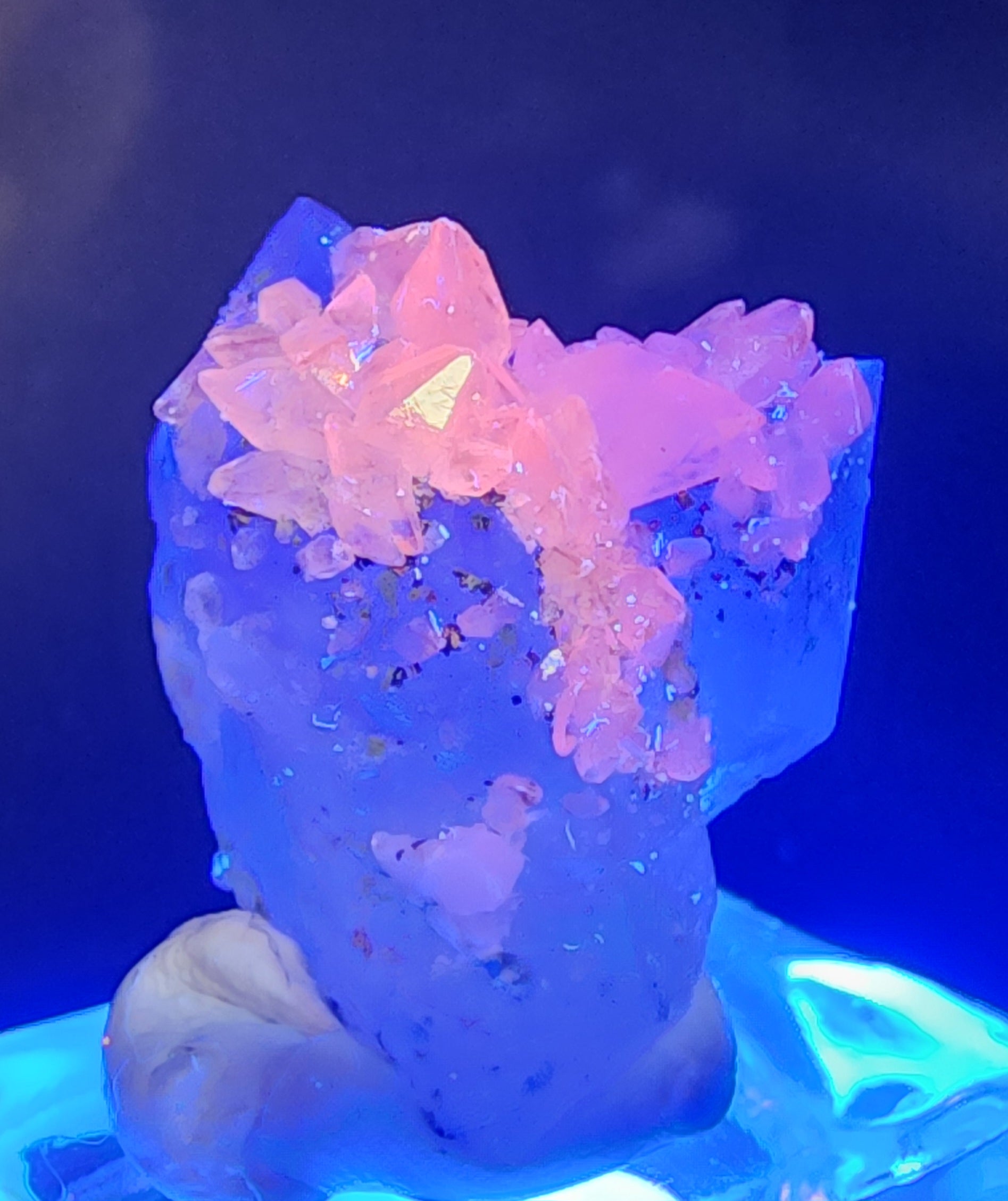 The Crystalary's Quartz v. Amethyst and Calcite from Tonglushan Mine (SKU 3102) features vibrant blue crystals with clusters of pink translucent facets that glow under UV light, creating a luminous effect against a dark background.