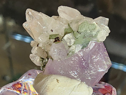 A cluster of Quartz var. Amethyst with greenish calcite from Tonglushan Mine, displayed on a decorative stand by The Crystalary (sku 3103), features clear and lavender crystals with sharp edges and a glassy finish, enhanced by reflective depth.