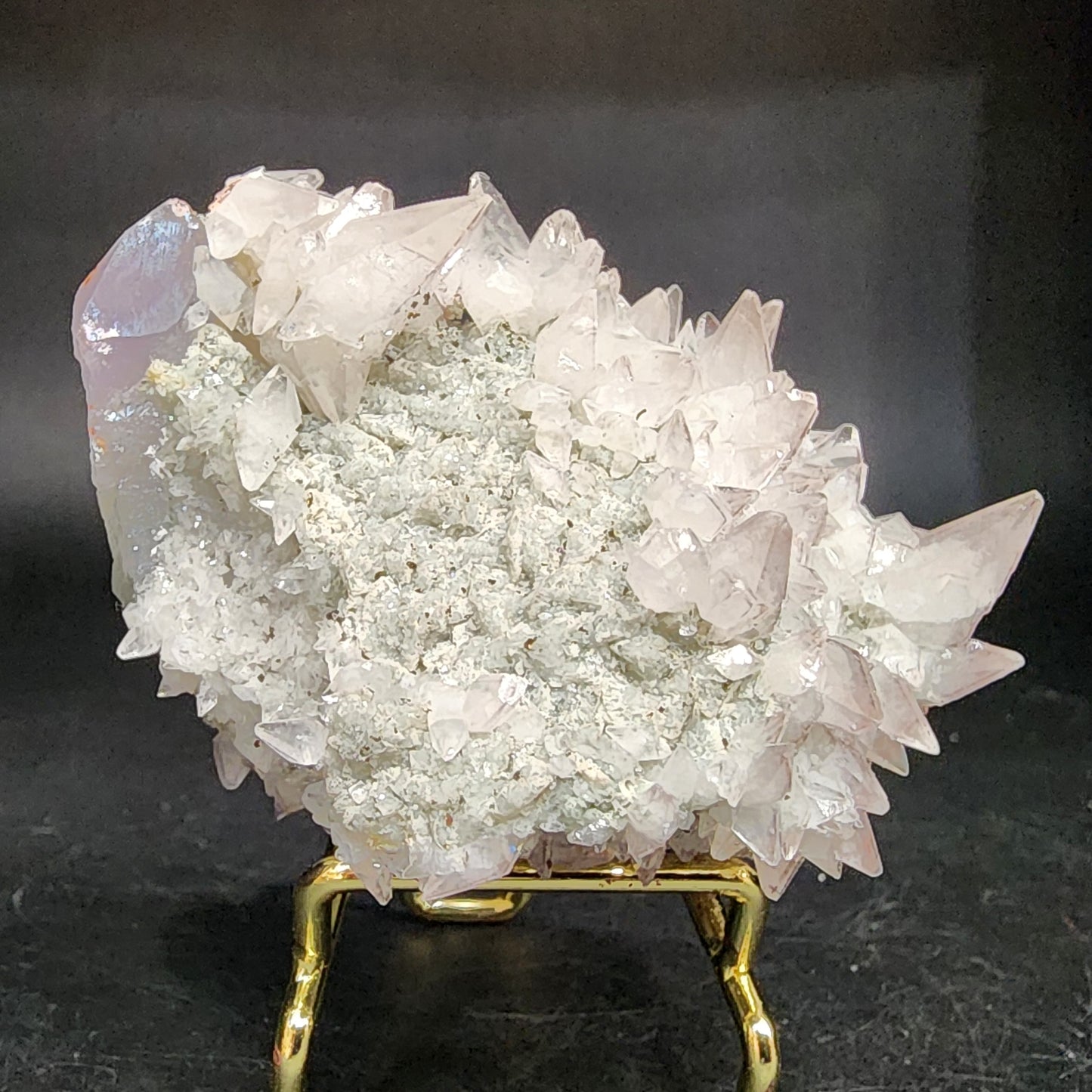 The Crystalary's Quartz v. Amethyst, Calcite from Tonglushan Mine features clear quartz crystals with pointed tips and amethyst hues on a metallic stand against a dark background, offering a jagged and sparkling surface (SKU 3105).