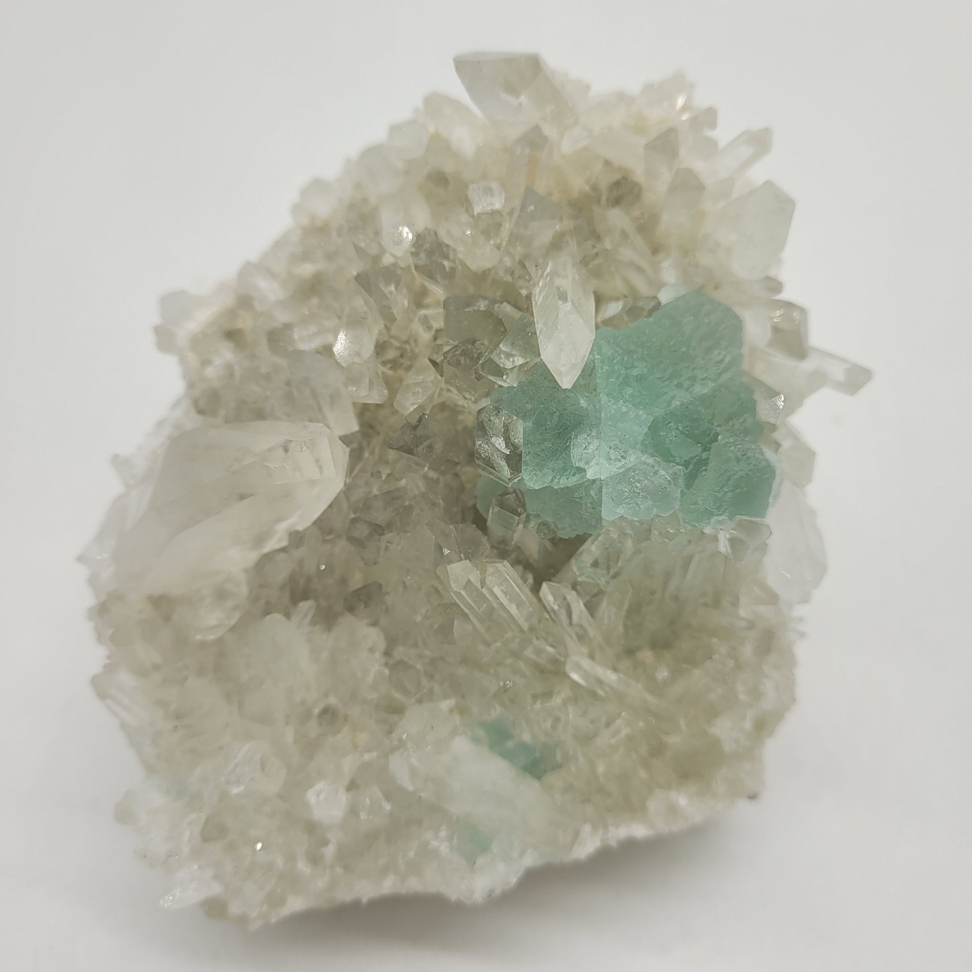 The Crystalary's Fluorite with Quartz (SKU 801) from Huayllapon Mine, Peru, features clear quartz crystals emerging from a white matrix, adorned with teal-blue and mint green mineral formations, showcasing varied shapes and sizes for a textured and sparkling appearance.