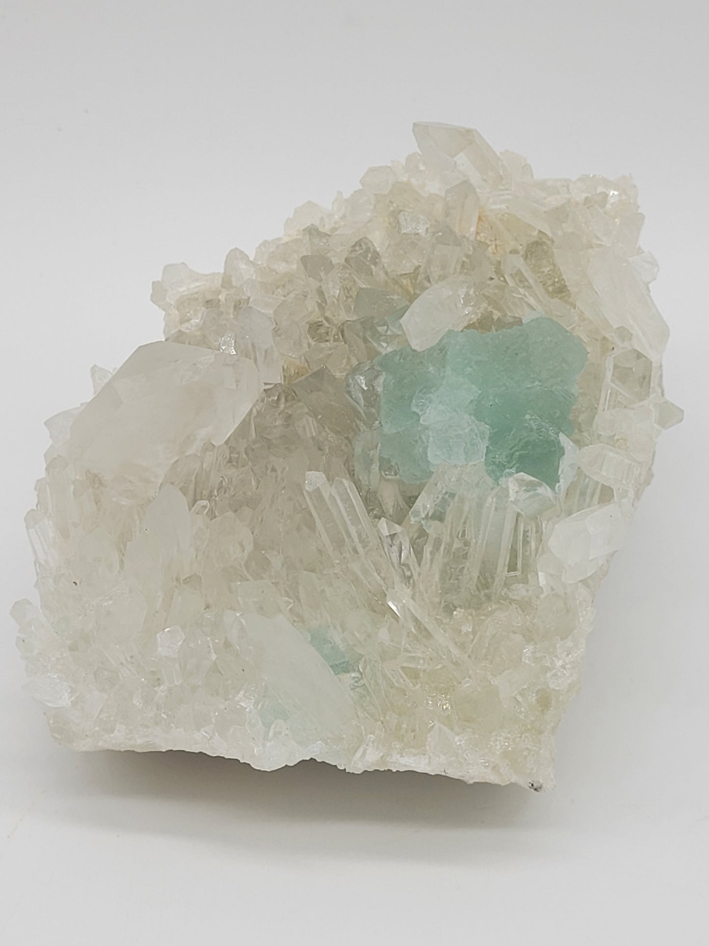 The Crystalary's Fluorite with Quartz- Huayllapon Mine (sku 801) features a cluster of clear quartz crystals and minty green fluorite on a white matrix, with varying sizes and transparent to translucent qualities that contrast against the green-tinted elements.