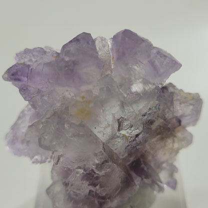 A close-up view of The Crystalary’s Fluorite from Huallanca, Ancash, Peru (SKU 802), beautifully displays the clear crystals and pointed edges with intricate formations and color variations against a plain background.