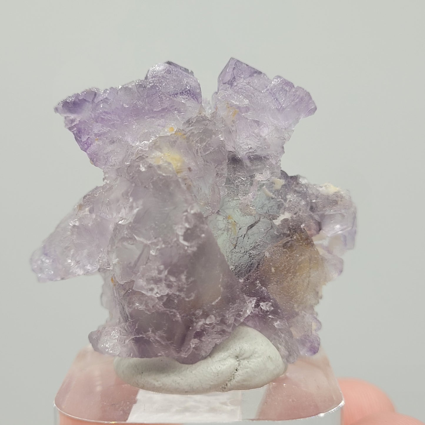 This exquisite Fluorite from Huallanca, Ancash, Peru (sku 802) by The Crystalary rests on an acrylic base. Its jagged crystals exhibit uneven textures and varying transparency, beautifully reflecting shades of purple and gray.