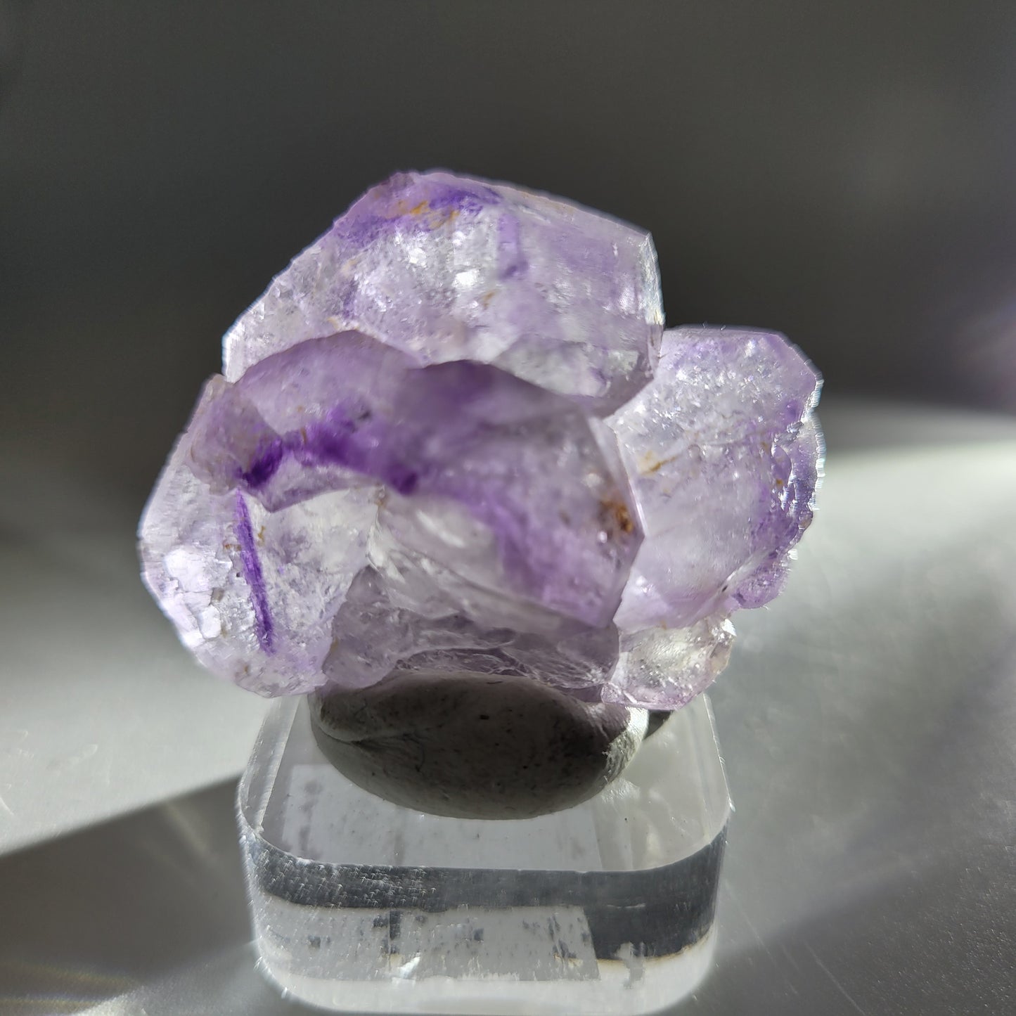 The Crystalary's Fluorite from Huallanca, Ancash, Peru (sku 804) beautifully resembles purple fluorite on a square clear base. Light passing through illuminates its natural colors and formations, evoking the shimmering majesty of Huallanca peaks.