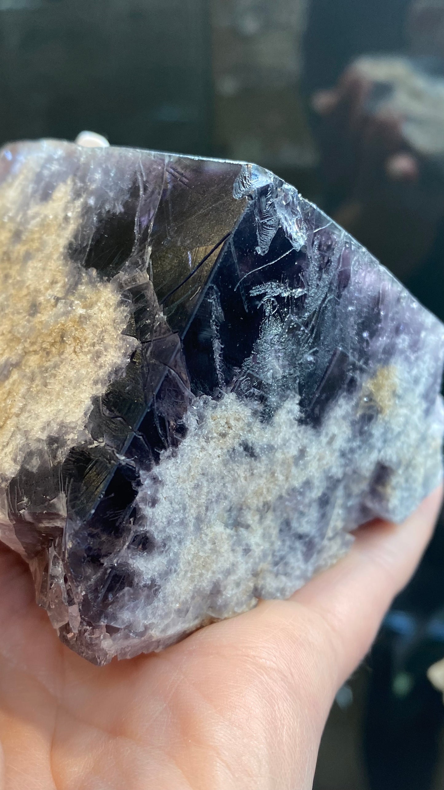 A hand displays a specimen of **Fluorite** from the **Purple Rain Pocket** at the **Lady Annabella Mine**, featuring deep purple and beige sections. The glossy crystalline purple areas create a striking contrast with the textured beige portions, showcasing its natural beauty as light illuminates it. This stunning piece from **The Crystalary**, SKU 3020, highlights its esteemed origin in Eastgate, Weardale, Co. Durham, England.