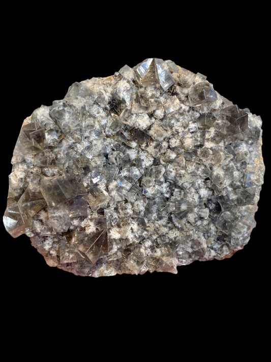 A close-up of a hand holding a cluster of jagged, grayish crystal formations from the Diana Maria Mine in Co. Durham showcases the translucent and densely packed surface of The Crystalary's Fluorite- Smoky Rabbit Pocket (sku3016), creating an intricate texture.