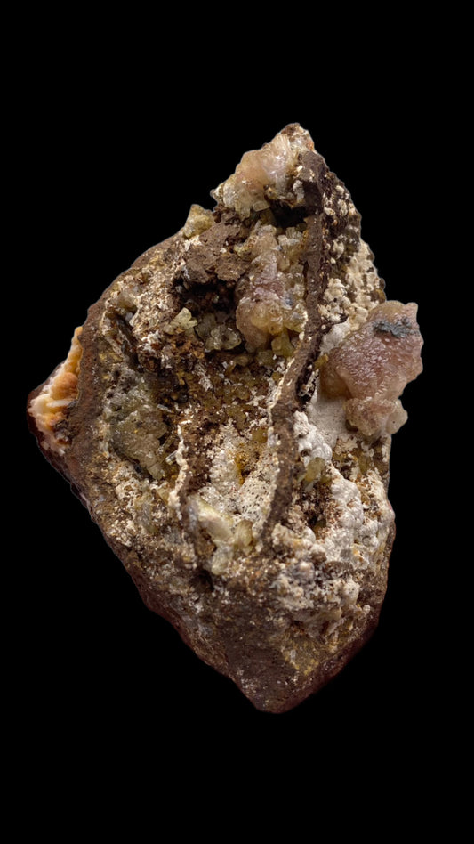 A detailed close-up of a rugged, irregularly shaped rock from the Ojuela Mine, featuring a blend of earthy brown, gray, and off-white hues. The rock surface is adorned with Manganoan-bearing purple Adamite from The Crystalary, giving it a textured and rugged appearance against a black background.