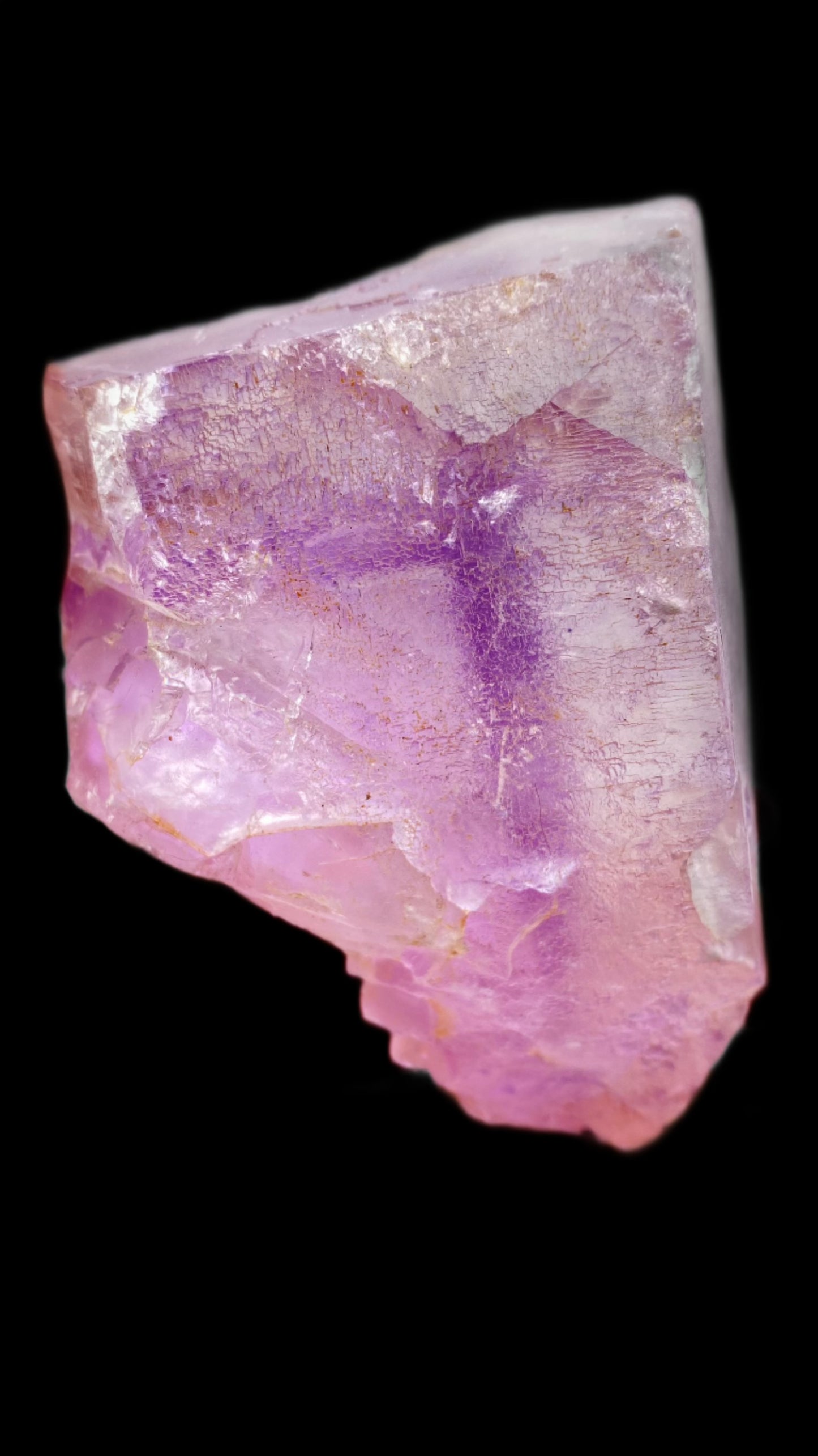 A close-up of a raw fluorite mineral named "Fluorite- Lead Hill, Cave-In-Rock, Hardin County, Illinois, USA" from The Crystalary showcases a jagged shape with predominantly pink and purple hues. Its rough surface features visible striations and color gradients that transition from deep purple to lighter pink, all set against a black background. This stunning specimen is reminiscent of those found in Cave-In-Rock.