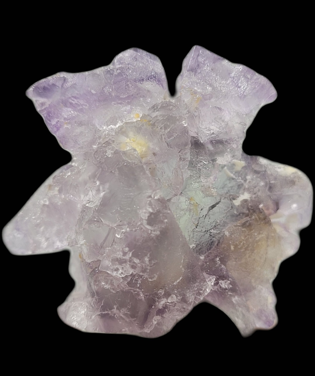 A close-up of a textured, frosted Fluorite specimen by The Crystalary, with translucent purple and light blue hues and jagged edges, set against a black background. Resembling those found in Huallanca, Ancash, Peru (SKU: 802).