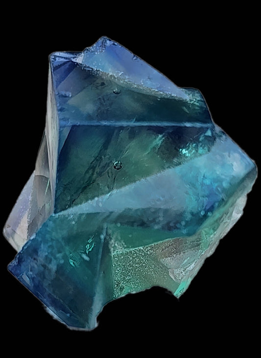 A large, intricate crystal from the Diana Maria Mine by The Crystalary sits on a black background. The Fluorite Mini from Frosterley, Weardale, Co. Durham exhibits superb clarity, with sharp edges and smooth surfaces revealing varying shades of blue and green within.