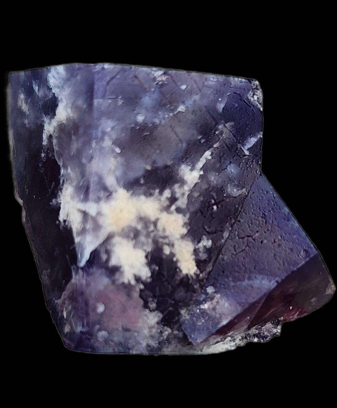 From The Crystalary, behold the Fluorite - Yum Yum Pocket, a stunning specimen from the renowned Diana Maria Mine in Weardale, Co Durham, UK (sku122). This large piece showcases dark purple coloration with white mineral deposits on its surface. Set against a black background, it features sharp edges and smooth facets.