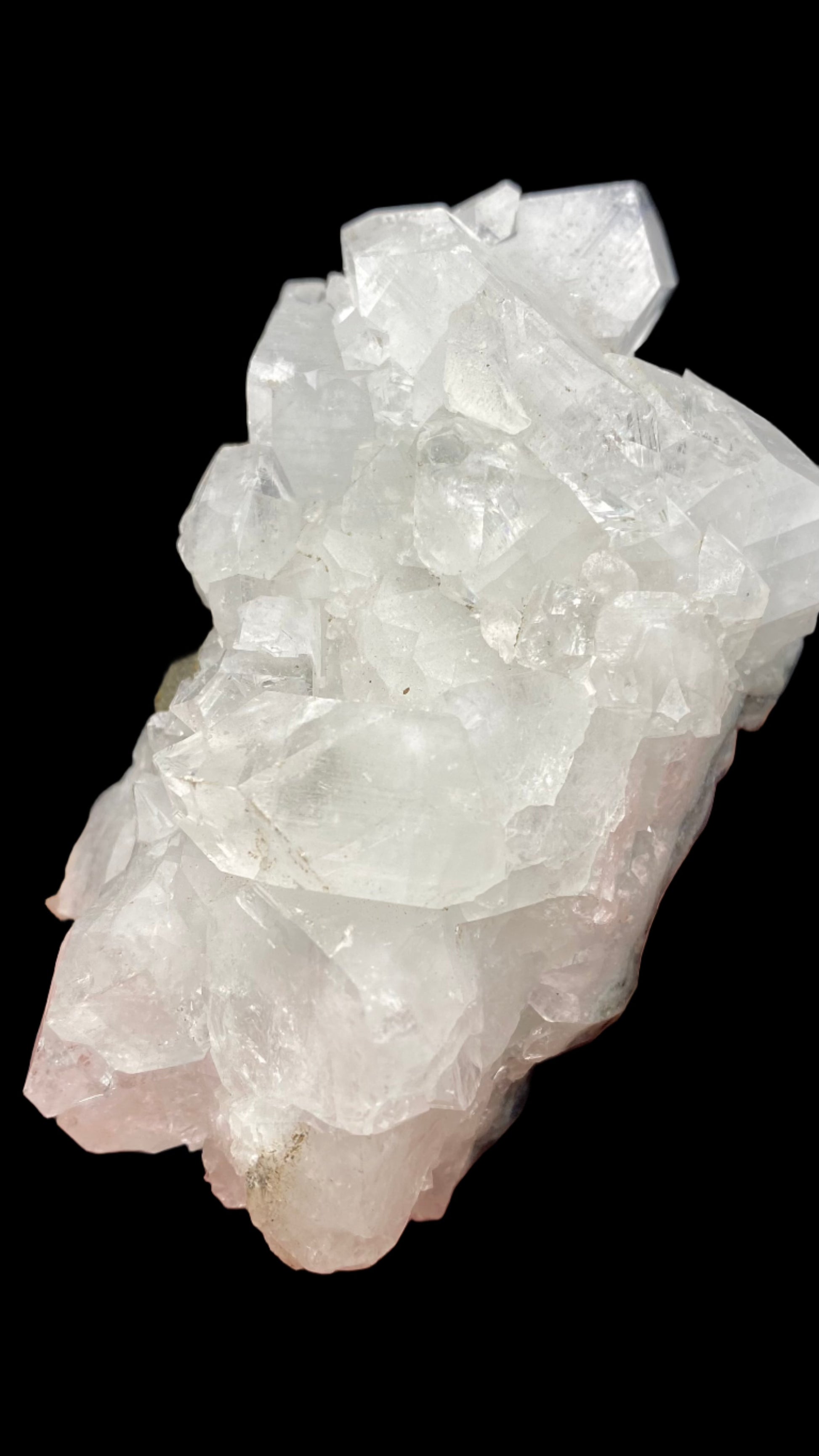 A stunning cluster of translucent white Apophyllite crystals from The Crystalary's collection at the Lonavala Quarry in Pune District, Maharashtra. These semi-transparent crystals feature jagged edges and are set against a solid black basalt matrix. Their irregular shapes and varying sizes give the formation a rugged and natural appearance, characteristic of Maharashtra's rich mineral treasures.