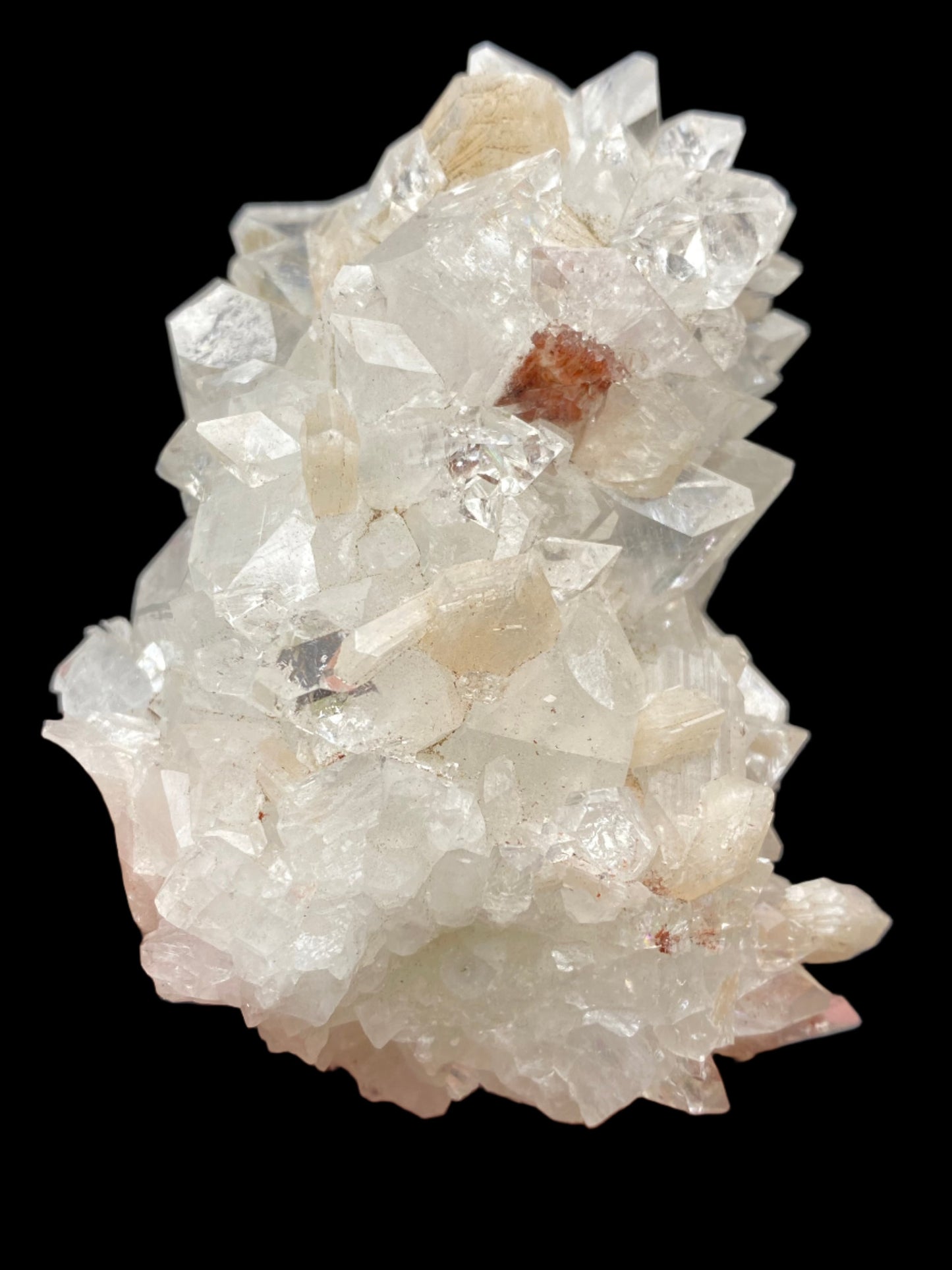 A cluster of transparent, hexagonal Apophyllite crystals with a few reddish inclusions, displayed against a solid black background. The crystals exhibit a clear, glassy luster and intricate prismatic formations reminiscent of Diamond Apophyllite from the Lonavala Quarry. This exquisite piece is brought to you by The Crystalary, sourced directly from the Lonavala Quarry in the Pune District, Pune Division, Maharashtra, India.