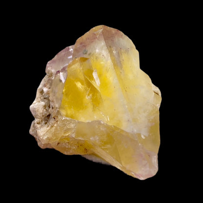 Close-up of a translucent yellow *Fluorite - Annabel Lee Mine, Harris Creek, Hardin County, Illinois, USA* crystal with rough edges on a black background. This *The Crystalary* crystal features irregular shapes and white and light purple mineral inclusions.