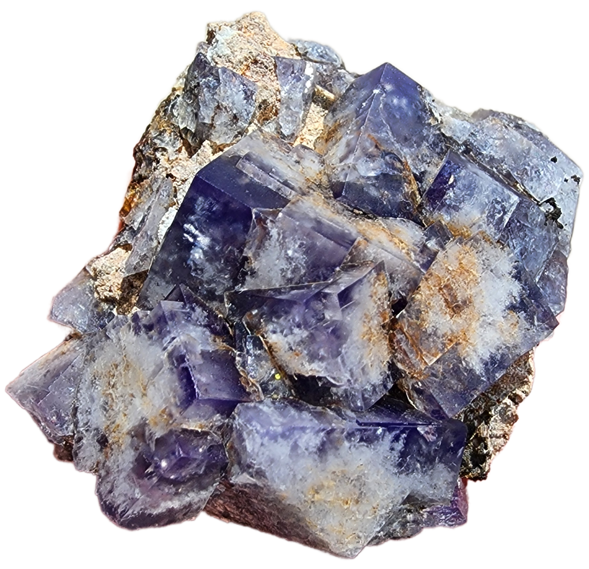 A Fluorite-Milky Way Pocket from Diana Maria Mine, Weardale, Co Durham, UK by The Crystalary features a stunning array of deep to light purple prismatic crystals with transparent clarity and daylight fluorescence. These crystals are set against a rough, earthy matrix background interspersed with patches of white and beige mineral deposits.