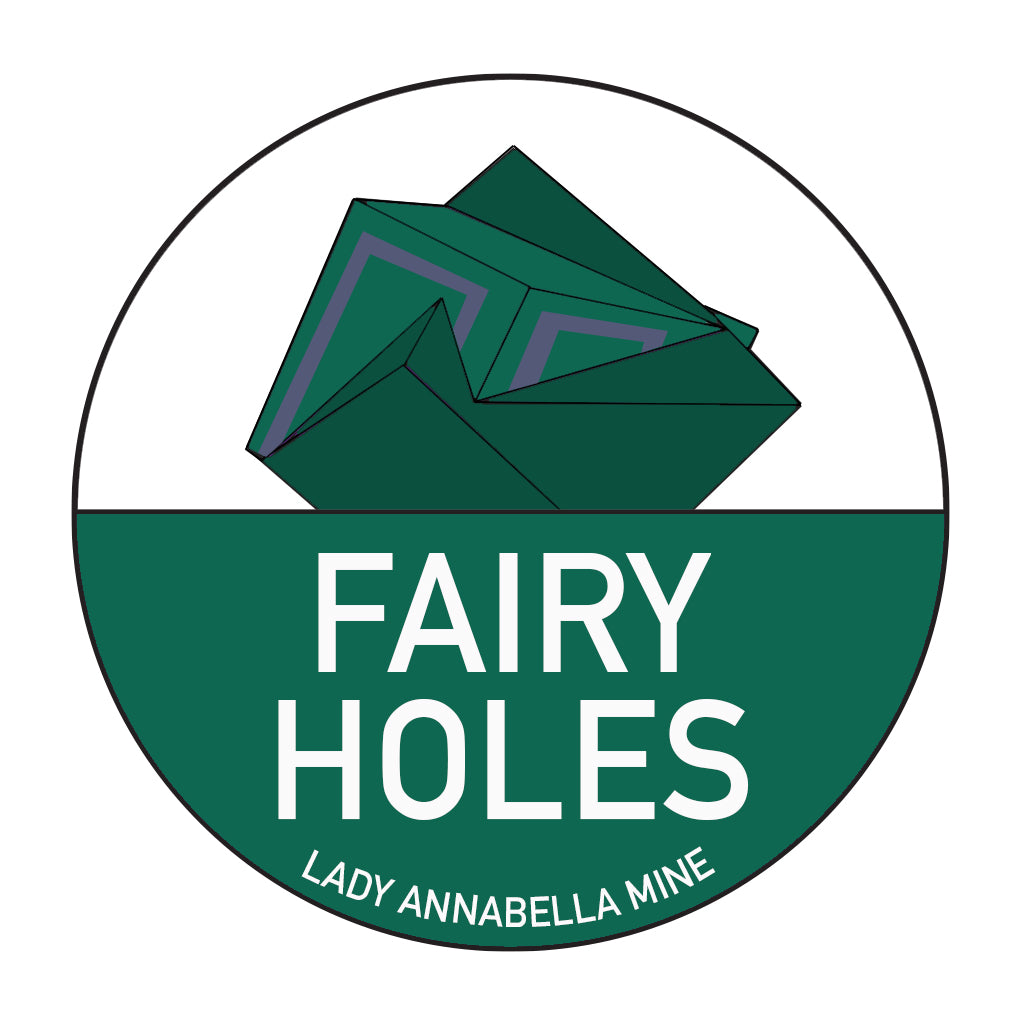 The Lady Annabella Passport Stickers from The Crystalary feature a circular logo with a green lower half and an upper half depicting crystalline shapes made of green, folded paper. The logo is rendered in full color with "FAIRY HOLES" displayed prominently in white text, and "LADY ANNABELLA MINE" written below in a smaller font – perfect for stickers!