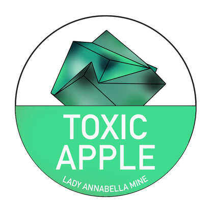 A circular logo showcasing a stylized green gemstone above the bold white text "TOXIC APPLE." Below that, in smaller white letters, it says "Lady Annabella Mine." The background is horizontally divided with white on top and green on the bottom, making it ideal for full-color Lady Annabella Passport Stickers from The Crystalary.