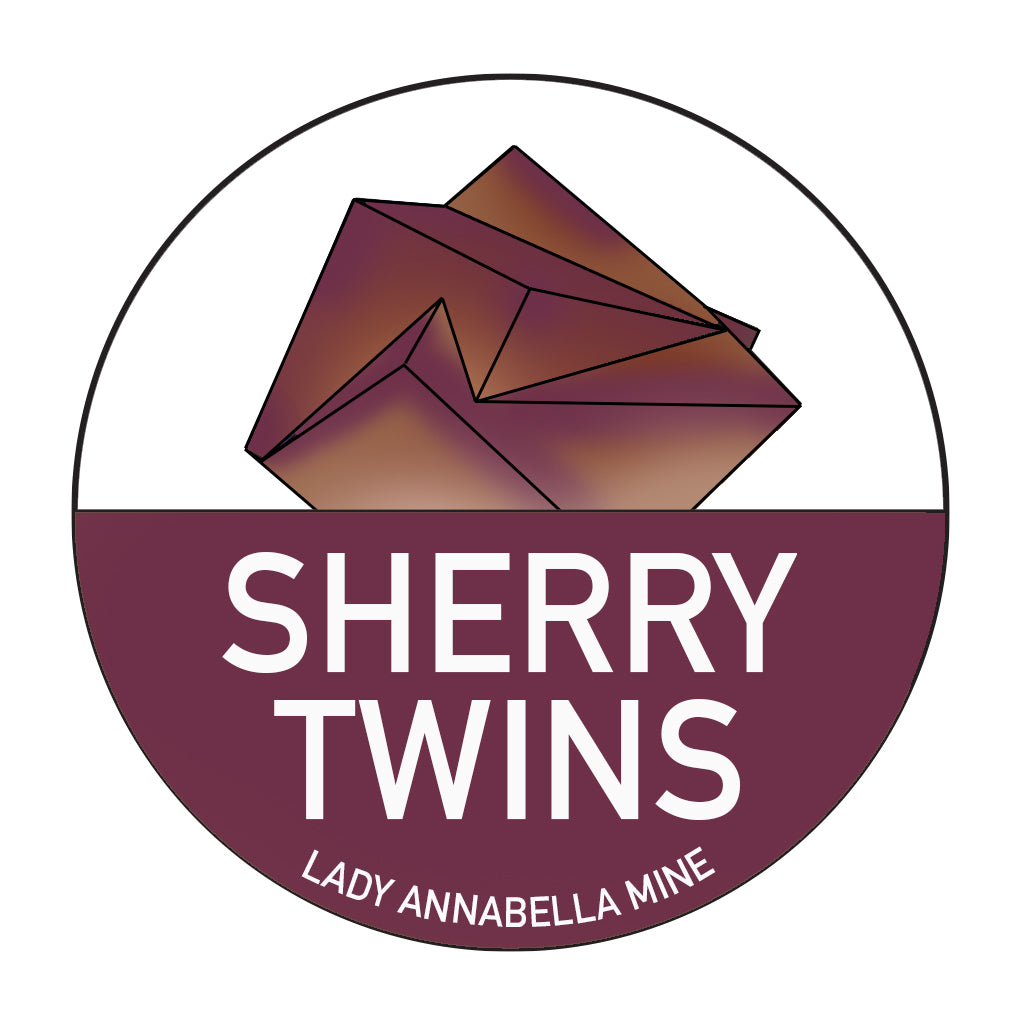 A circular logo featuring a geometric crystal design in shades of brown and purple at the top. Below the crystal, "SHERRY TWINS" is prominently displayed in bold white letters on a maroon background, reminiscent of the Lady Annabella Passport Stickers by The Crystalary. At the bottom, smaller text reads "LADY ANNABELLA MINE".