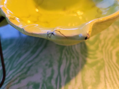 Close-up of a funky chartreuse divided serving dish on a green and white marbled surface. Visible cracks radiate from the edge, highlighting the dish’s wear and age. The lighting casts soft shadows, emphasizing the texture and details of this mid-century hors d'oeuvre dish handmade in California by The Crystalary's Hollywood Ceramics line.