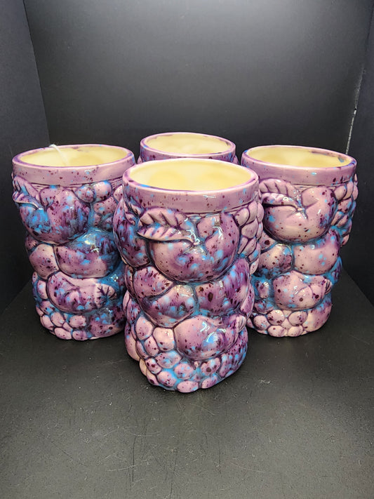 A set of four Inarco STYLE Ceramic Fruit Tumblers from The Crystalary, each adorned with purple and blue speckles, are arranged closely together on a dark surface with a black background. These hand-painted tumblers showcase a unique design and glossy finish.