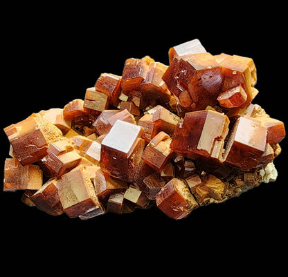 A striking arrangement of reddish-brown, cubic vanadinite crystals with smooth surfaces is showcased elegantly on a black background. From the esteemed Mibladen mining district in Midelt Province, Drâa-Tafilalet Region, Morocco, these Vanadinite crystals from The Crystalary (sku 3076) boast a vibrant and glossy appearance that accentuates their geometric shape and natural texture.