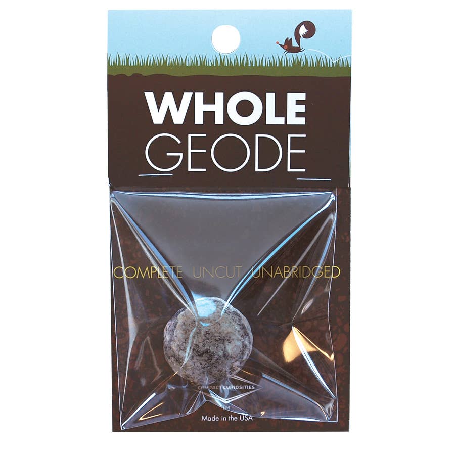 A packaged Whole Geode from Copernicus Toys' Compact Curiosities Break Your Own Geode series is displayed. The top of the packaging reads "WHOLE GEODE," with "COMPLETE, UNCUT, UNABRIDGED" just below. The geode is visible through clear plastic wrapping, making it perfect as a science toy or for a STEM demonstration. Additionally, the top of the package features a small dinosaur illustration.